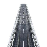 Empty asphalt road covered with snow disappearing into the distance photo