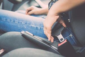 A person sitting in the back seat of a car with their hands on the seat belt photo
