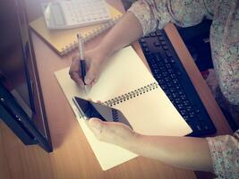 A person sitting at a desk with a notebook and a pen photo