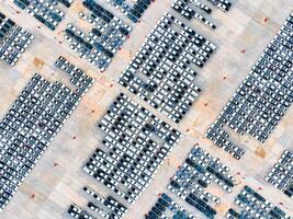 Aerial view of automotive logistics. Factory parking lot filled with rows of new cars. Modern vehicle production and distribution. Import or export operations at expansive port terminal facilities photo
