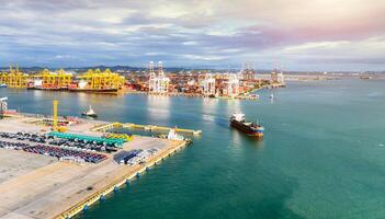 Aerial view of a large stock of new cars parked at a port terminal. Automotive industry logistics and transport operations. Import and export of vehicles by ship, with containers ready global trade. photo