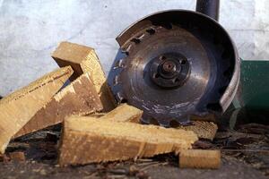 Circular saw blade slices through logs, scattering wood shavings and debris around a rustic workshop photo