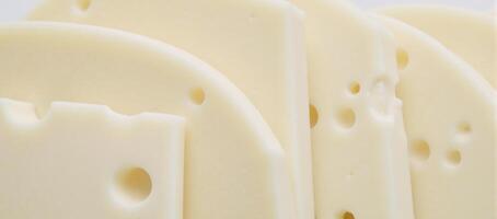 Closeup image of Swiss cheese slices against a neutral backdrop showcasing their distinctive hole patterns photo