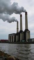 A polluted river surrounded by towering smokestacks from an industrial factory photo