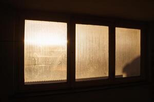 Warm morning sunlight filters through a frosted window, casting soft glows and shadows in apartment building. A serene depiction of peaceful beginnings and tranquil home environments. photo