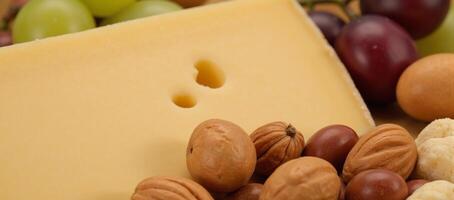Closeup image Large EmmentalEmmenthaler cheese with grapes nuts photo