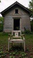 A hauntingly beautiful scene features an abandoned cottage and its weathered chair amidst decay and neglect photo