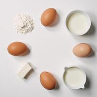 Topdown view Baking essentials eggs flour milk cottage cheese arranged against a textured white backdrop with ample room for copy photo