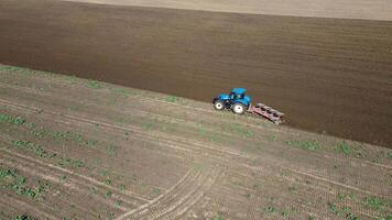 A tractor plowing a farmer's field in autumn. A drone flies over the tractor working in the field. video