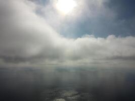 Aerial view. The drone flies over foggy and fluffy clouds. Blue sky sun and sea fog. Abstract aerial nature summer ocean sunset sea and sky background. Vacation, travel and holiday concept photo