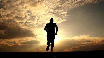 Silhouette of a Man Running at Sunset with Dramatic Sky and Clouds in the Background photo