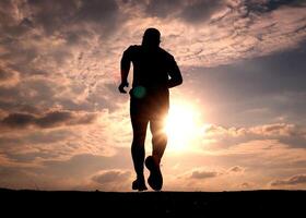 Silhouette of a Runner at Sunset with Dramatic Sky and Clouds in the Background photo