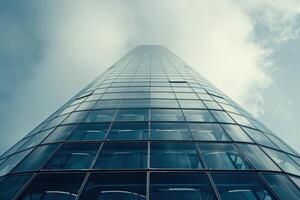 Modern glass skyscraper towering into cloudy sky photo