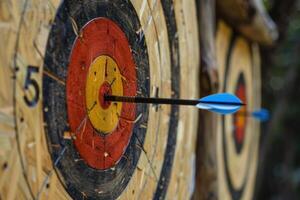 Arrow hitting the center of archery target on wooden background photo