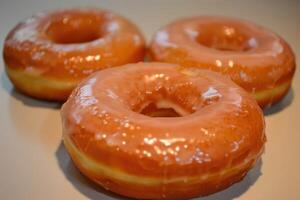 Three delicious glazed doughnuts arranged with a selective focus on a neutral background photo
