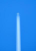 Airplane Flying High in Clear Blue Sky with Contrail - Minimalist Aerial Photography photo