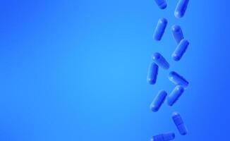 Blue capsules falling against a gradient blue background. Medical background with copy space. Stock photo