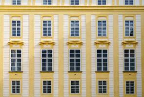 The historic European building facade features ornate yellow walls with barred windows and intricate architectural details. Perfect for history, travel, and architecture projects. photo
