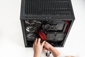 A focused individual is seen installing various hardware components into a sleek black computer case. The case is open, revealing the interior, while the persons hands adjust the components with precision. photo