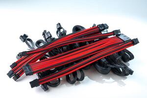 A black and red computer cable isolated on a white background. The cable is made up of multiple wires, each covered in a red and black sleeve. The cable is used to connect a computer to a power source. photo