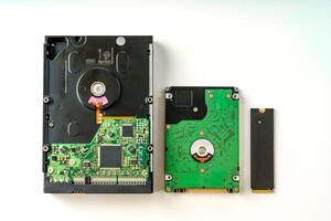 The image displays three distinct types of electronic storage devices including a hard disk drive, a solid-state drive, and a flash drive. Each device is isolated against a clean white background. photo