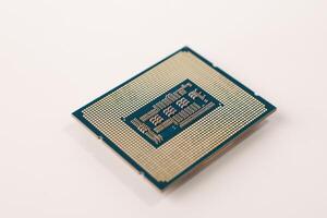 The image features the back of a computer processor with gold pins, set against a white background. This small square chip connects to the motherboard, executing computer program instructions. photo