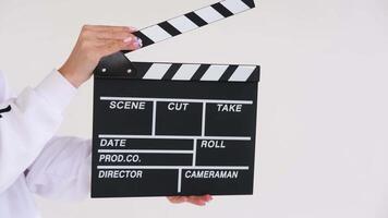 Film director in a white sweater is clapping a movie slate on a white background video