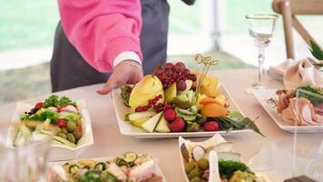 Waiter in a pink sweater placing a plate of fresh fruit on a beautifully arranged banquet table with care and precision video