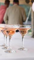 Woman picks up a glass of rose wine from a table full of drinks at a catered event in this slow motion video