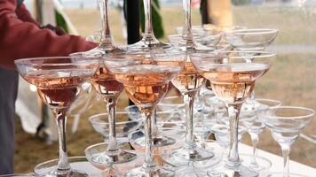 A waiter delivers clean empty glasses to a buffet table against a background of a pyramid of champagne glasses video