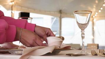 Event planner folding a napkin on a plate in slow motion showcases elegance and attention to detail in table setting video