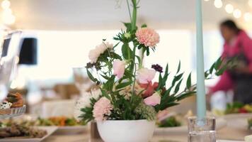 Capturing a vibrant wedding table arrangement with fresh flowers and food, as a server elegantly moves in slow motion in the background video