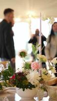 Guests embrace warmly at an elegant event in the background, with a flower arrangement in the center of the frame video