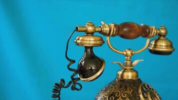 Vintage phone in brown and gold color on a bright blue background, shows off its classic design in smooth motion video