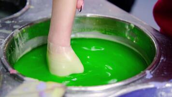 The child's hand in wax is dipped into a green liquid to give it color video