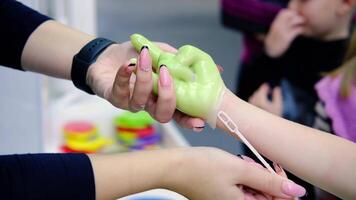 The master is about to remove green wax from a child's hand to make a keepsake figure. video