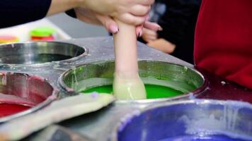 Exploring slow motion hand dipping in vibrant liquid mold during a crafting demonstration, capturing the creative process video