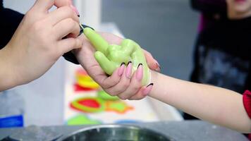 Green wax is removed from a child's hand to make a figure video