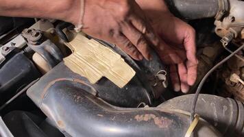 The mechanic is removing the car's air filter to clean it.Car service work at the garage video