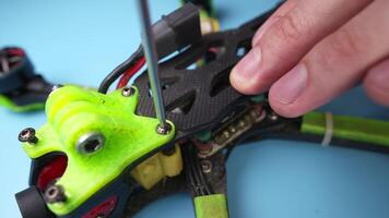 Close up of a hand screwdriver male craftsman unscrewing a fpv self-assembled drone on his desk. Shallow depth of field. Unscrewing and screwing video