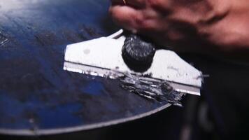 Female hands of a snowboard repairman cleaning wax off the sliding surface of a snowboard. Close-up with shallow depth of field. Low key video