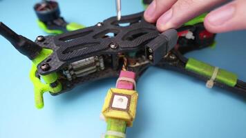 Close up of a hand screwdriver male craftsman unscrewing a fpv self-assembled drone on his desk. Shallow depth of field. Unscrewing and screwing video