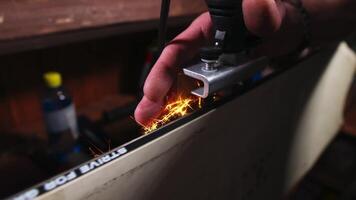 Close-up. Male hands sharpening the edge of a snowboard in a ski rental shop. Low key. Shallow depth of field. video