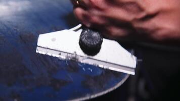 Snowboard sliding surface repair process. Close-up with shallow depth of field. The technician scrapes off excess wax applied to the snowboard. video