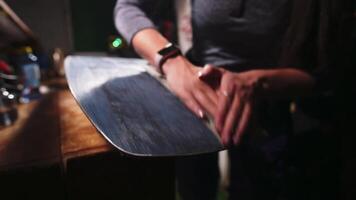 Female hands of a craftsman sanding the sliding surface of a snowboard. Snowboard alignment and repair. Low key. High contrast. Shallow depth of field. video