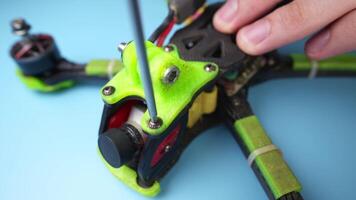 Close up of a hand screwdriver male craftsman unscrewing a fpv self-assembled drone on his desk. Shallow depth of field. Unscrewing and screwing video