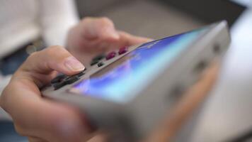 Close-up of female hands of young Caucasian woman holding retro game console. Girl playing retro games on portable game console. Shallow depth of field. Selective focus video