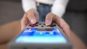 Close-up of female hands of young Caucasian woman holding retro game console. Girl playing retro games on portable game console. Shallow depth of field. Selective focus video