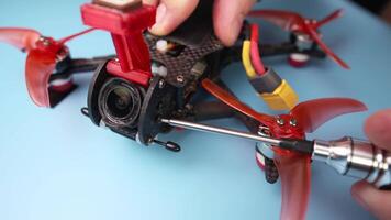 Close up of a hand screwdriver male craftsman unscrewing a fpv self-assembled drone on his desk. Shallow depth of field. Unscrewing and screwing video