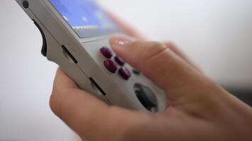 Close-up in shallow depth of field. Unrecognizable portable retro console in hands of young Caucasian woman. Girl plays retro games holding retro device for emulating old console games video